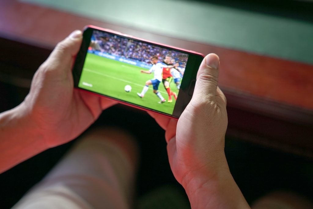 Torcedor que sabe onde assistir a Copa vendo o jogo no seu celular
