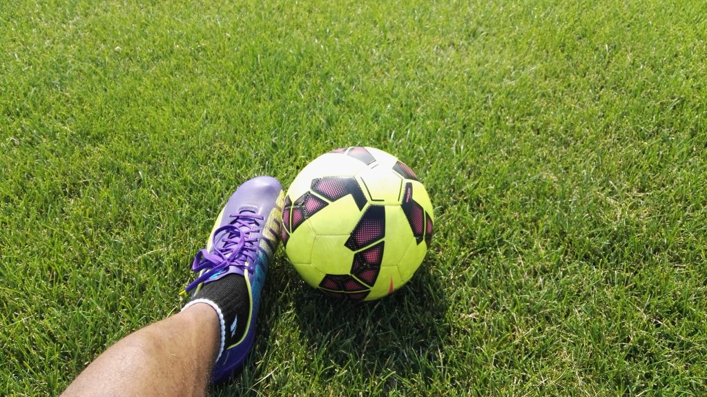 Pé de jogador ao lado de bola de futebol. 