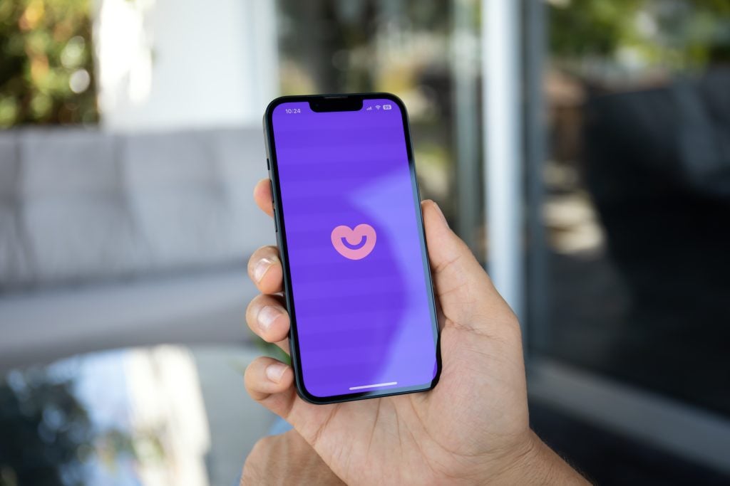 WoMan hands holding iPhone 14 with online Internet network service dating focused Badoo on the screen.