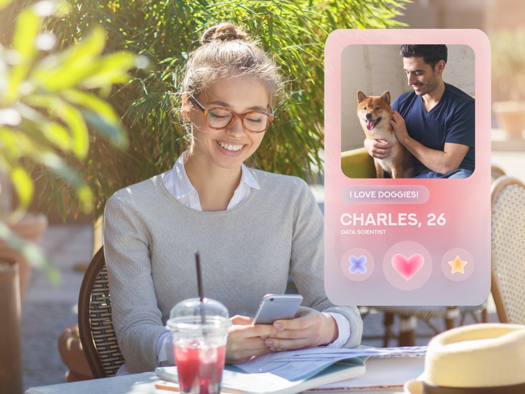 Young woman in stylish specs using dating app on mobile phone sitting in cafe outdoors, liking profile of handsome guy with dog, enjoying summer morning. Modern virtual relationships